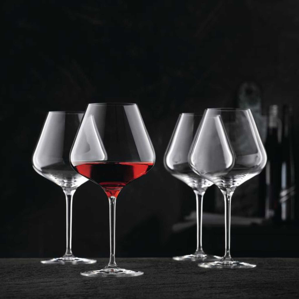 Nachtmann red wine ballon glasses with black background. One glass out of the four is filled with red wine.
